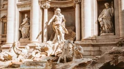 un grup de oameni stând și stând în fața fântânii trevi în italia