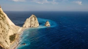 o insulă în mijlocul unui corp de apă cu roques de anaga în fundal în zakynthos