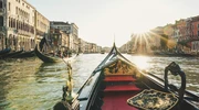 o barcă mică într-un corp de apă cu un oraș în fundal în italia