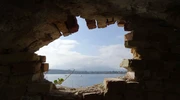 o vedere a unei clădiri de piatră care are un pod peste apă în grecia