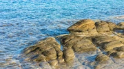o persoană care stă pe o stâncă lângă un corp de apă în peninsula halkidiki