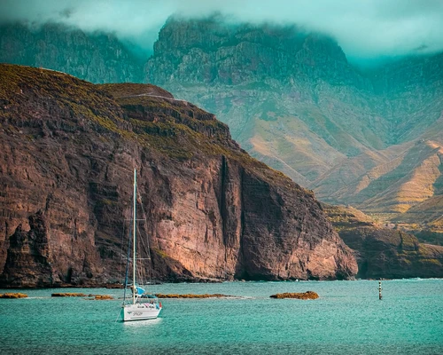 un corp mare de apă cu un munte în fundal în gran canaria