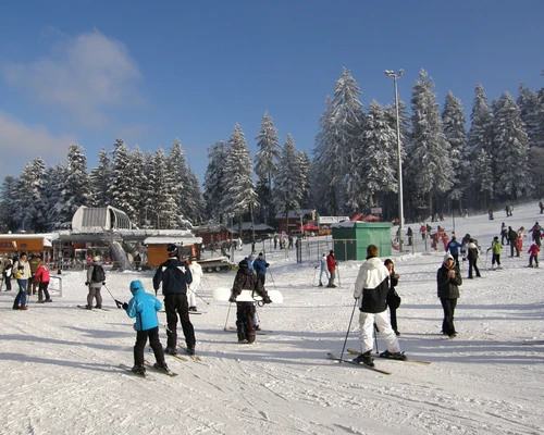 un grup de oameni călărind pe schiuri pe o pârtie acoperită cu zăpadă în borovets