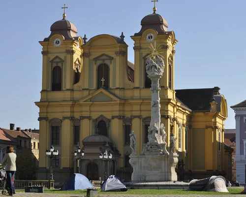 un grup de oameni care stau în fața unei biserici în timișoara