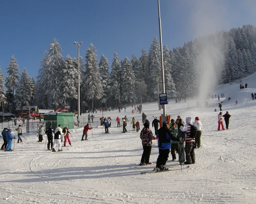 un grup de oameni călărind pe schiuri pe o pârtie acoperită cu zăpadă în borovets