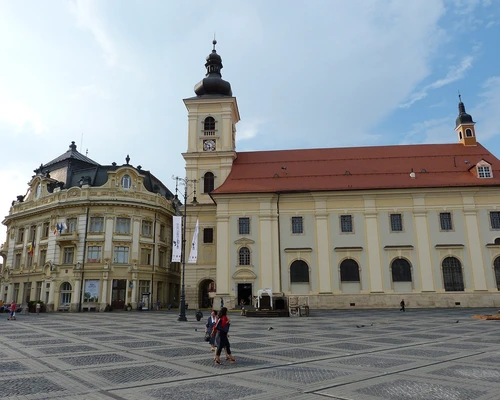 un grup de oameni care mergeau în fața unei clădiri în sibiu