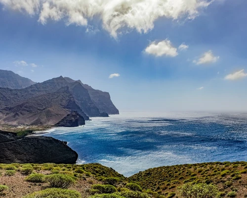 un corp mare de apă cu un munte în fundal în gran canaria