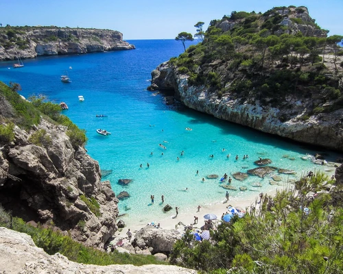 o plajă stâncoasă lângă un corp de apă cu parcul național calanques în fundal în mallorca