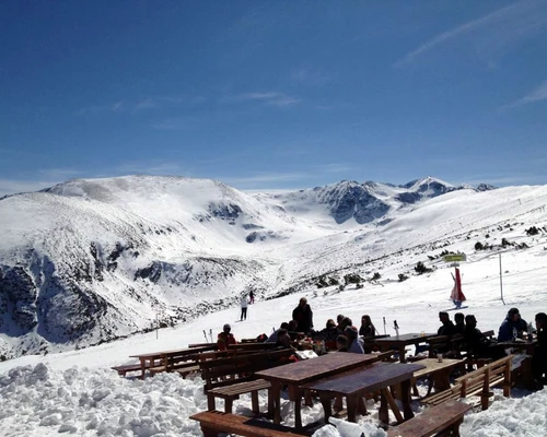 un grup de oameni care stă în vârful unei pante acoperite cu zăpadă în borovets