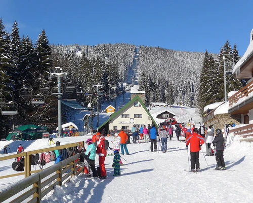 un grup de oameni care stă în vârful unei pante acoperite cu zăpadă în borovets