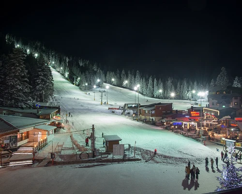 un grup de oameni călărind pe schiuri într-o noapte cu zăpadă în borovets